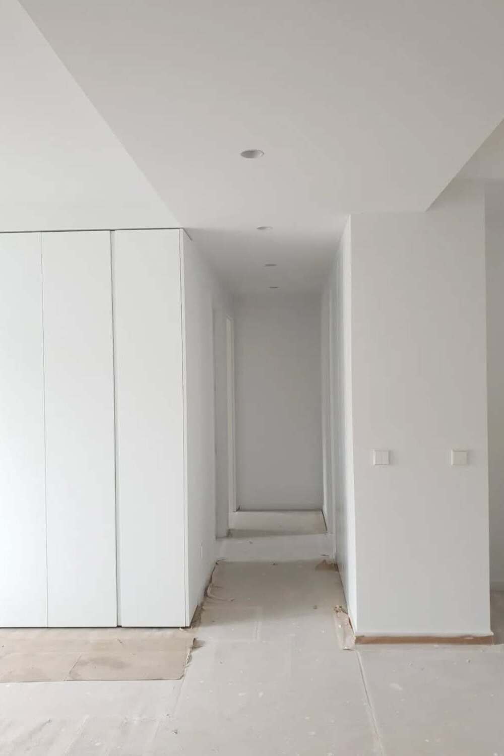 Pasillo de vivienda en reforma con paredes blancas